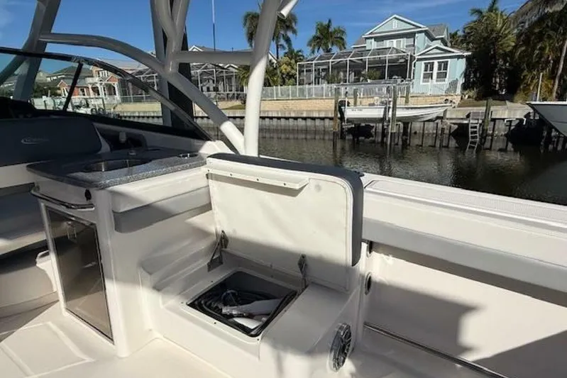 E Komo Mai Yacht Photos Pics 2021 Robalo R317 Dual Console boat interior with open storage, dockside view.