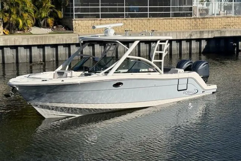 E Komo Mai Yacht Photos Pics 2021 Robalo R317 Dual Console boat on calm water near a dock.