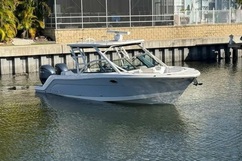 E Komo Mai Yacht Photos Pics 2021 Robalo R317 Dual Console boat on calm water near a dock.