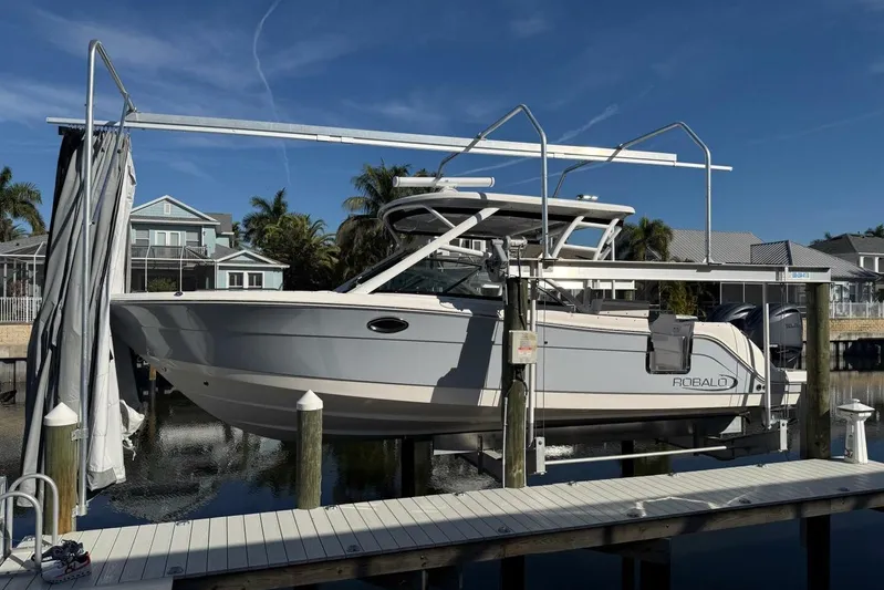 E Komo Mai Yacht Photos Pics 2021 Robalo R317 Dual Console boat on lift at dockside, sunny day.