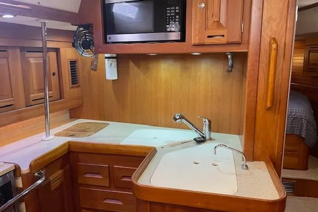 Alegria Yacht Photos Pics 2007 Tartan 4400 yacht kitchen with wooden cabinetry, sink, and microwave.