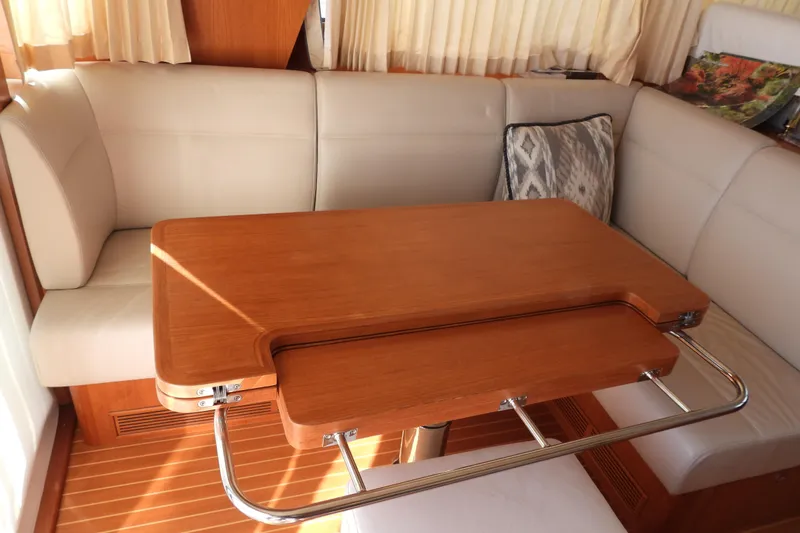  Yacht Photos Pics Interior of 2015 Grand Banks 46 Eastbay SX with wooden table and beige seating.