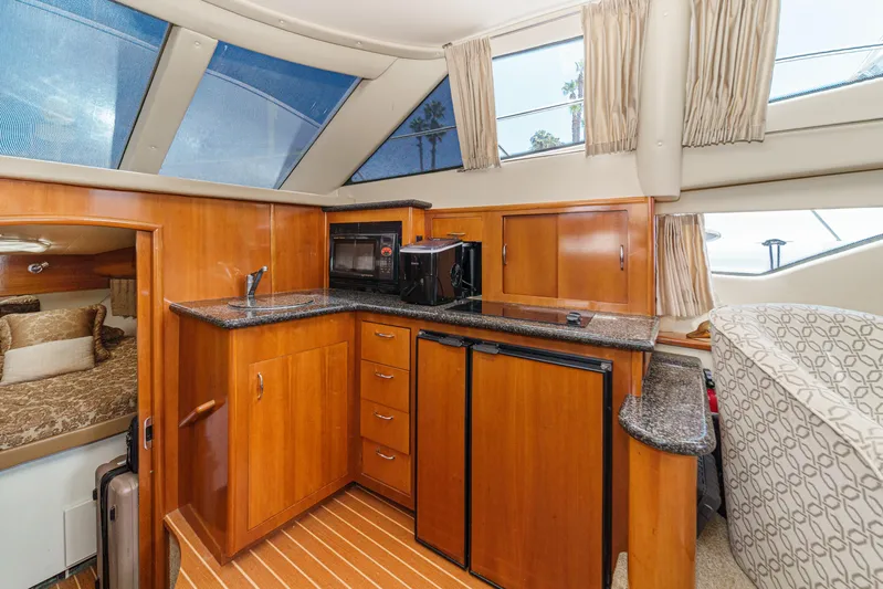  Yacht Photos Pics 2005 Carver 41 Cockpit Motor Yacht interior with kitchenette, wood cabinetry, and cozy sleeping area.