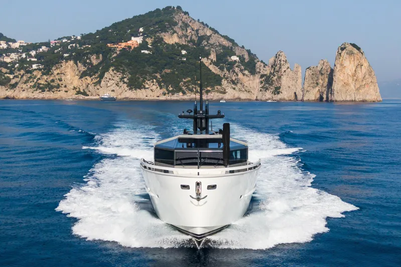 Milu' Yacht Photos Pics Arcadia Yachts A85 (2019) cruising near rocky coastline, clear blue waters.