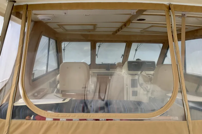 Lionheart Yacht Photos Pics 2006 Sabre 38 Hard Top Express interior with beige seating and helm, viewed through clear enclosure.