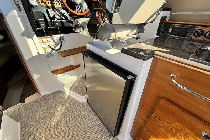  Yacht Photos Pics Interior of 2026 Cutwater C-288 Coupe featuring helm, fridge, and wooden cabinetry.