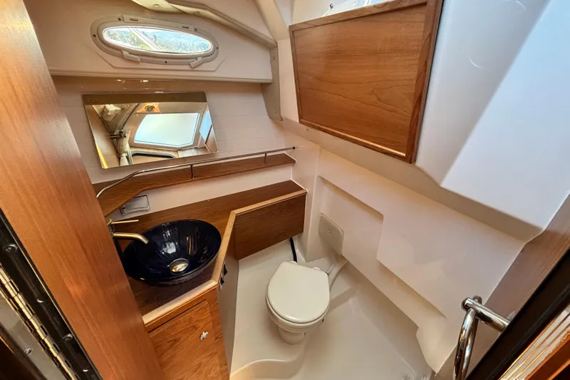  Yacht Photos Pics 2026 Cutwater C-288 Coupe bathroom with wooden cabinetry, modern sink, and compact toilet.