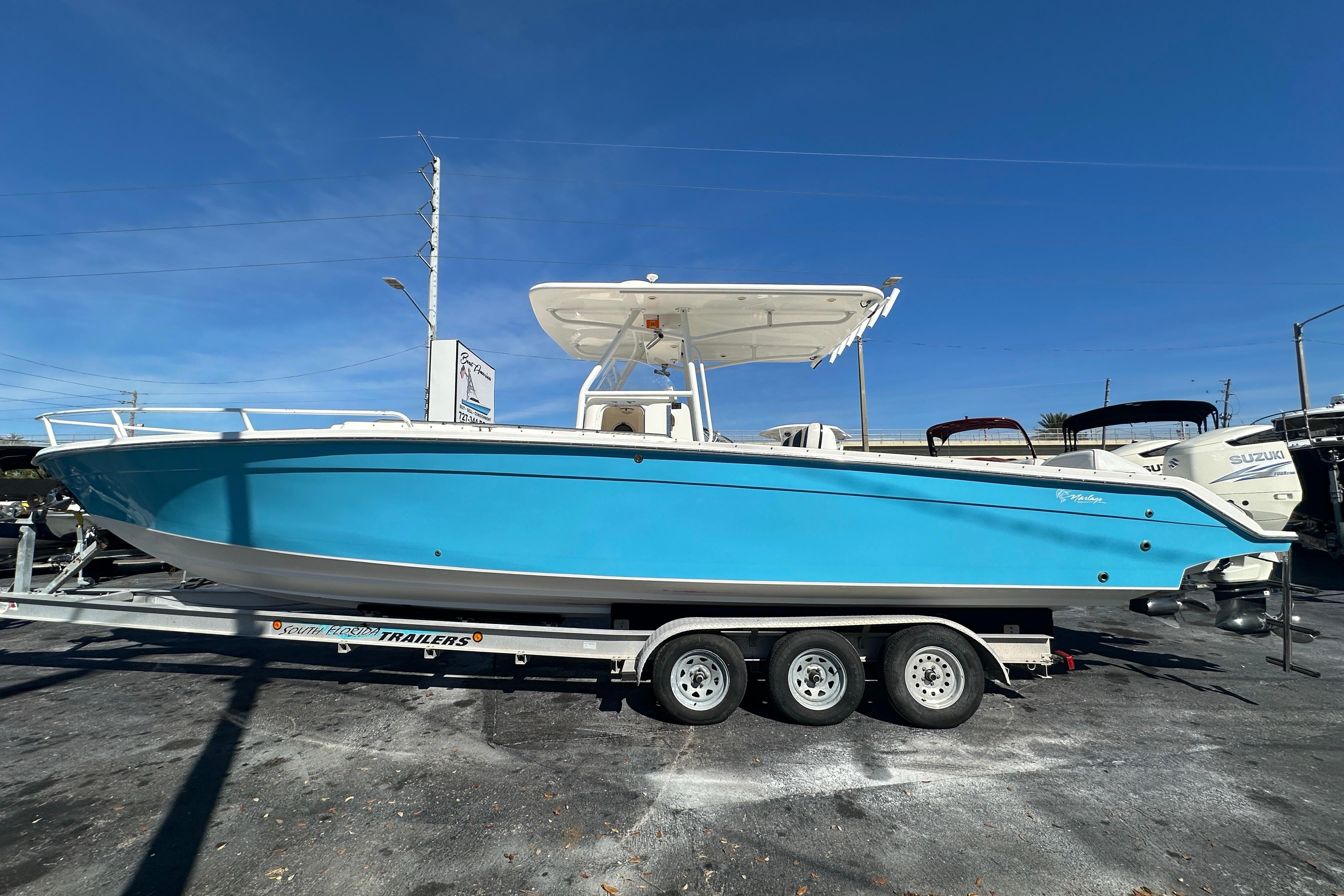 2004 Marlago 35 FS boat on trailer, vibrant blue hull, clear sky background.