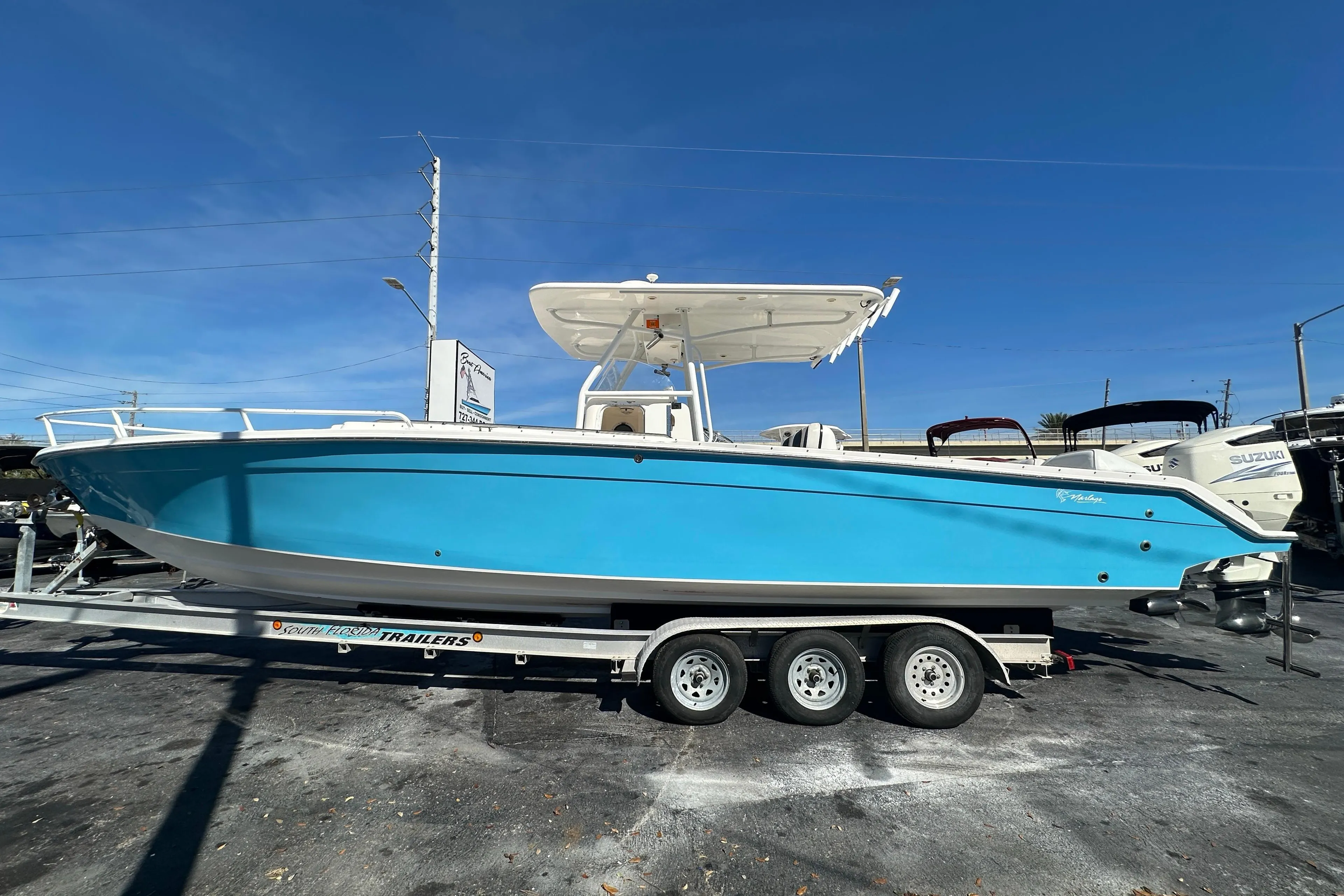 2004 Marlago 35 FS boat on trailer, vibrant blue hull, clear sky background.