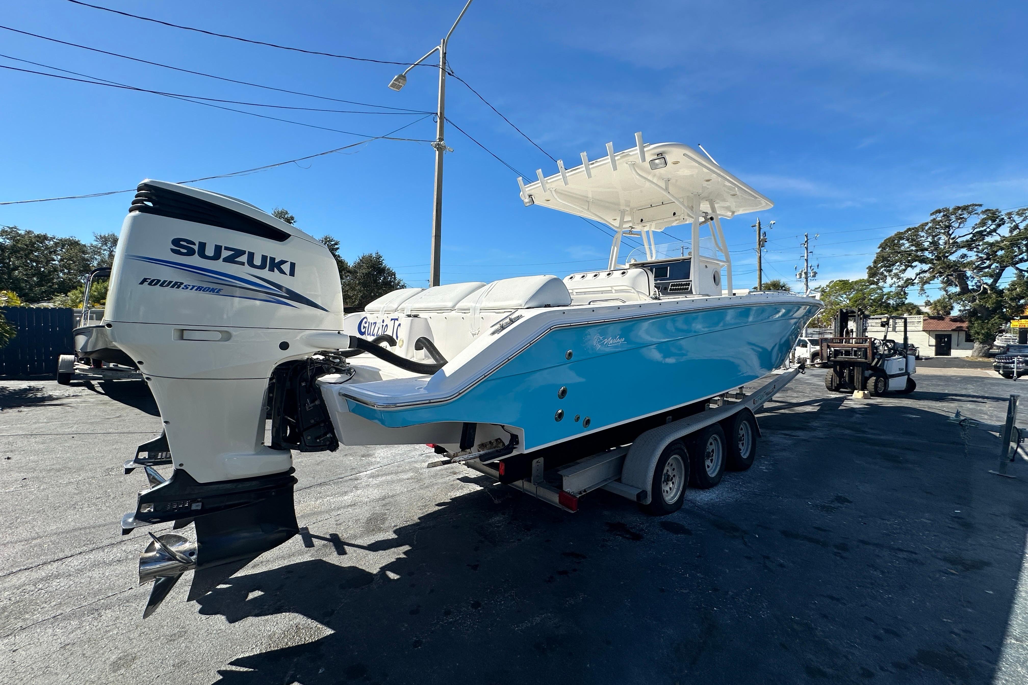 2004 Marlago 35 FS boat with Suzuki outboard engine on a trailer, parked outdoors.