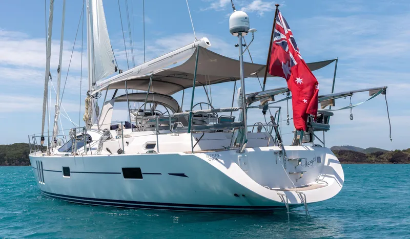 Margot Yacht Photos Pics Sailing yacht Oyster 575, 2013 model, anchored in clear blue waters with a red flag.