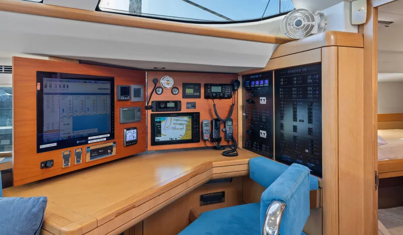 Margot Yacht Photos Pics Navigation station of 2013 Oyster 575 yacht with control panels and blue seating.