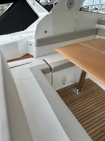 Small Batch Yacht Photos Pics 2016 Jeanneau Leader 36 boat interior with cushioned seating and wooden table.