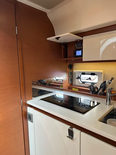 Small Batch Yacht Photos Pics 2016 Jeanneau Leader 36 kitchen area with modern appliances and wooden cabinetry.