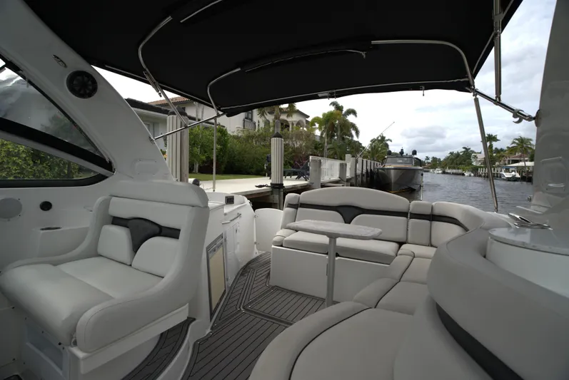  Yacht Photos Pics 2017 Rinker 320 Express Cruiser interior with plush seating and canopy, docked by a canal.