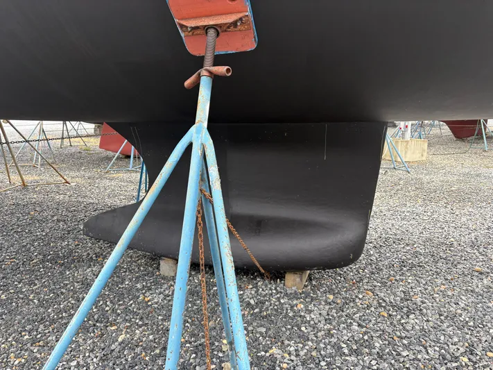 At Last Yacht Photos Pics 2004 Beneteau Oceanis 473 sailboat keel on gravel, supported by blue stands.