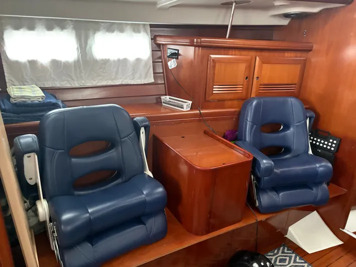 At Last Yacht Photos Pics Interior of 2004 Beneteau Oceanis 473 with blue leather seats and wooden cabinetry.