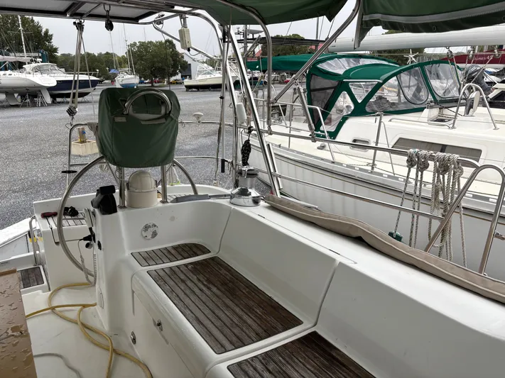 At Last Yacht Photos Pics 2004 Beneteau Oceanis 473 sailboat cockpit with wooden seating and marina view.