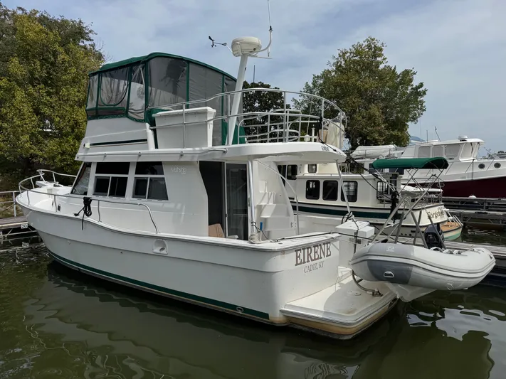 Eirene Yacht Photos Pics 2001 Mainship 390 yacht docked, featuring green canopy and inflatable dinghy, surrounded by other boats.