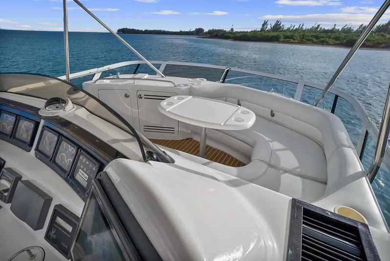 Our Trade Yacht Photos Pics 2001 Sea Ray 480 Sedan Bridge yacht interior with seating and table, overlooking serene water and shoreline.