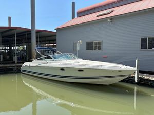 2000 Formula 330 SS boat docked beside a building, under clear blue sky.