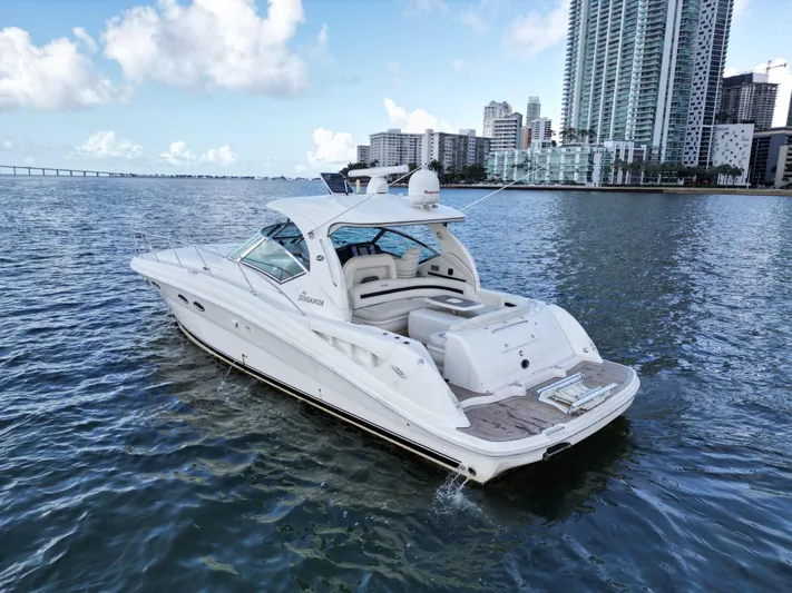  Yacht Photos Pics 2005 Sea Ray 44 Sundancer yacht cruising near city skyline on a sunny day.