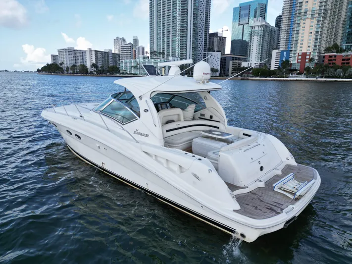  Yacht Photos Pics 2005 Sea Ray 44 Sundancer yacht cruising near city skyline.