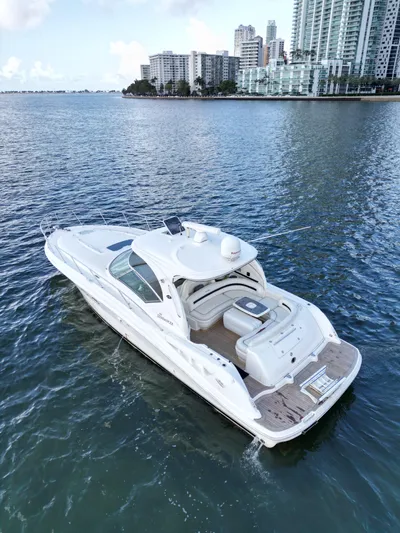  Yacht Photos Pics 2005 Sea Ray 44 Sundancer yacht cruising near city skyline on calm waters.