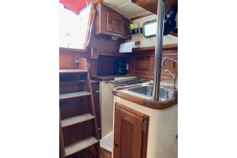 Irish Rose Yacht Photos Pics Interior of 1995 Pacific Seacraft Crealock 34 sailboat, featuring wooden cabinetry and compact kitchen.