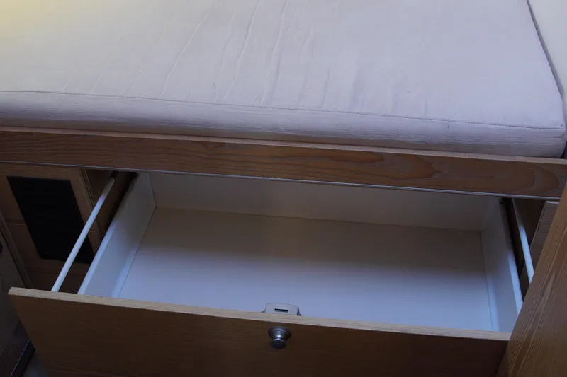  Yacht Photos Pics Open wooden drawer under cushioned seat in 2013 Hanse 575 yacht interior.