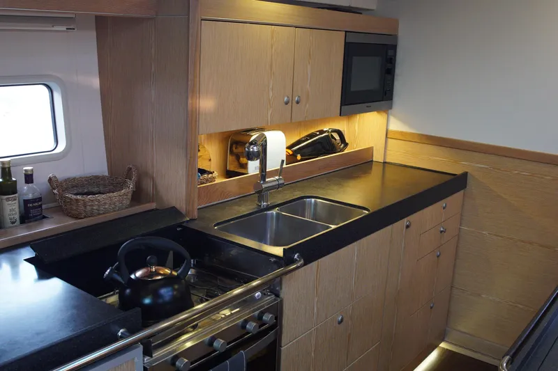  Yacht Photos Pics Modern kitchen interior of 2013 Hanse 575 yacht with wooden cabinets and stainless steel sink.