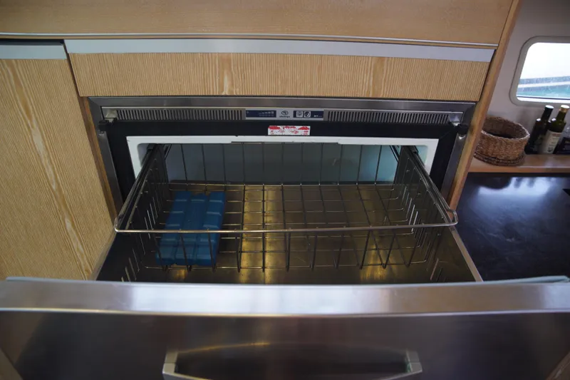  Yacht Photos Pics Open freezer drawer in 2013 Hanse 575 yacht kitchen, featuring wooden cabinetry and countertop.