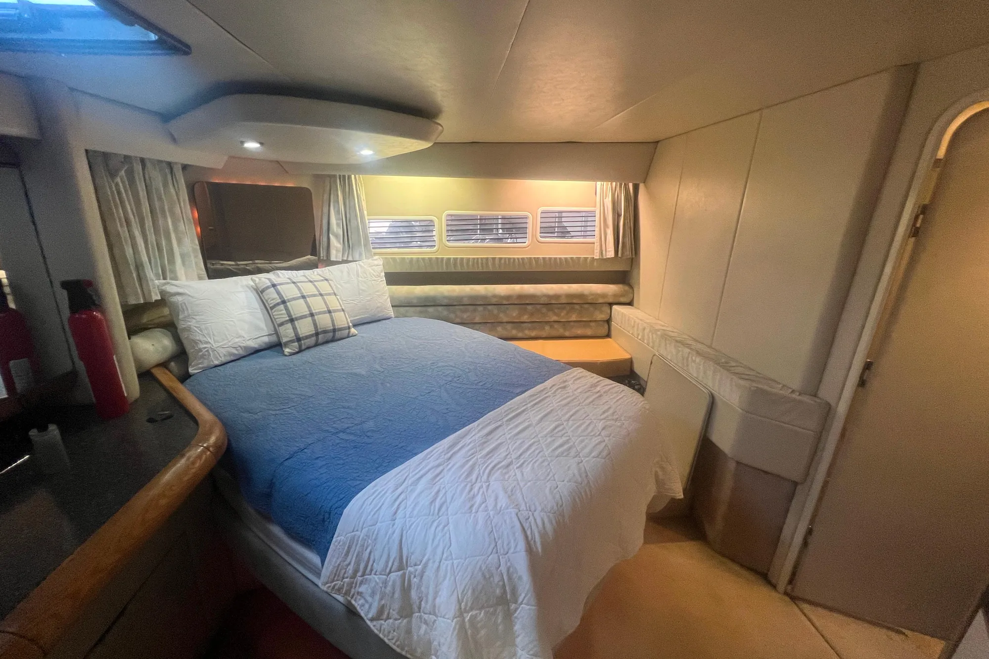 Cozy bedroom interior of 1989 Bayliner 4285 Avanti yacht with bed and porthole windows.