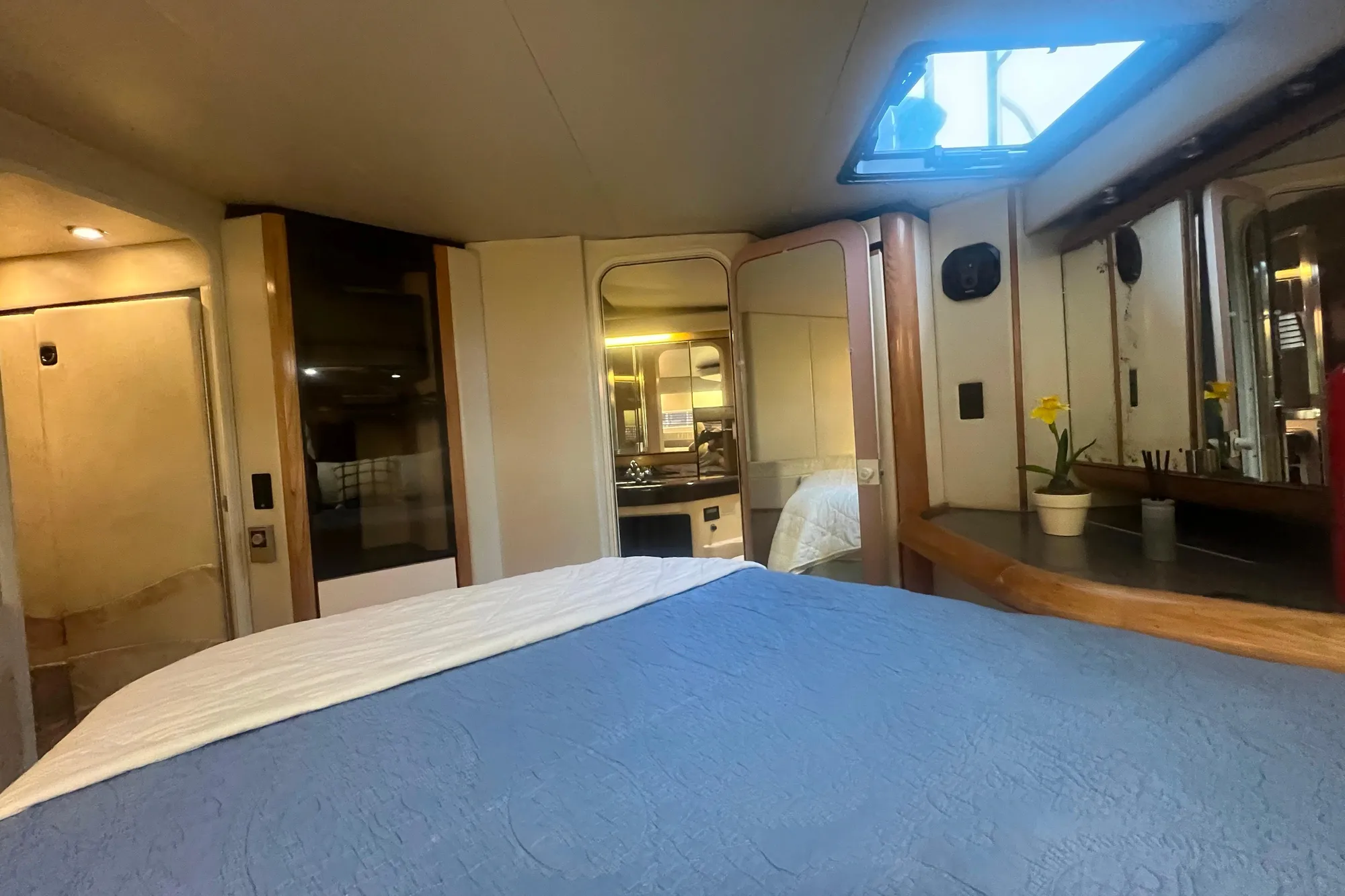 1989 Bayliner 4285 Avanti cabin interior with bed, skylight, and potted plant.