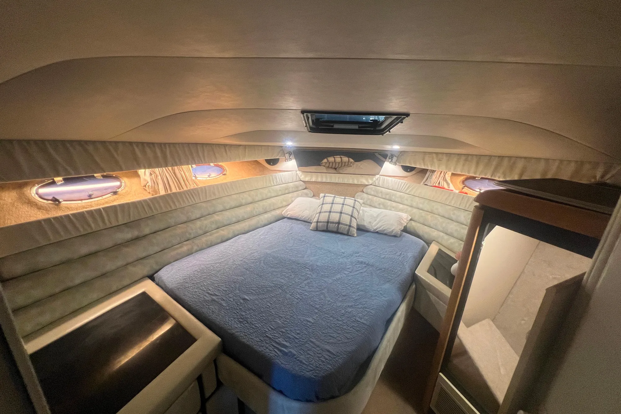 1989 Bayliner 4285 Avanti cabin interior with bed, portholes, and cozy lighting.
