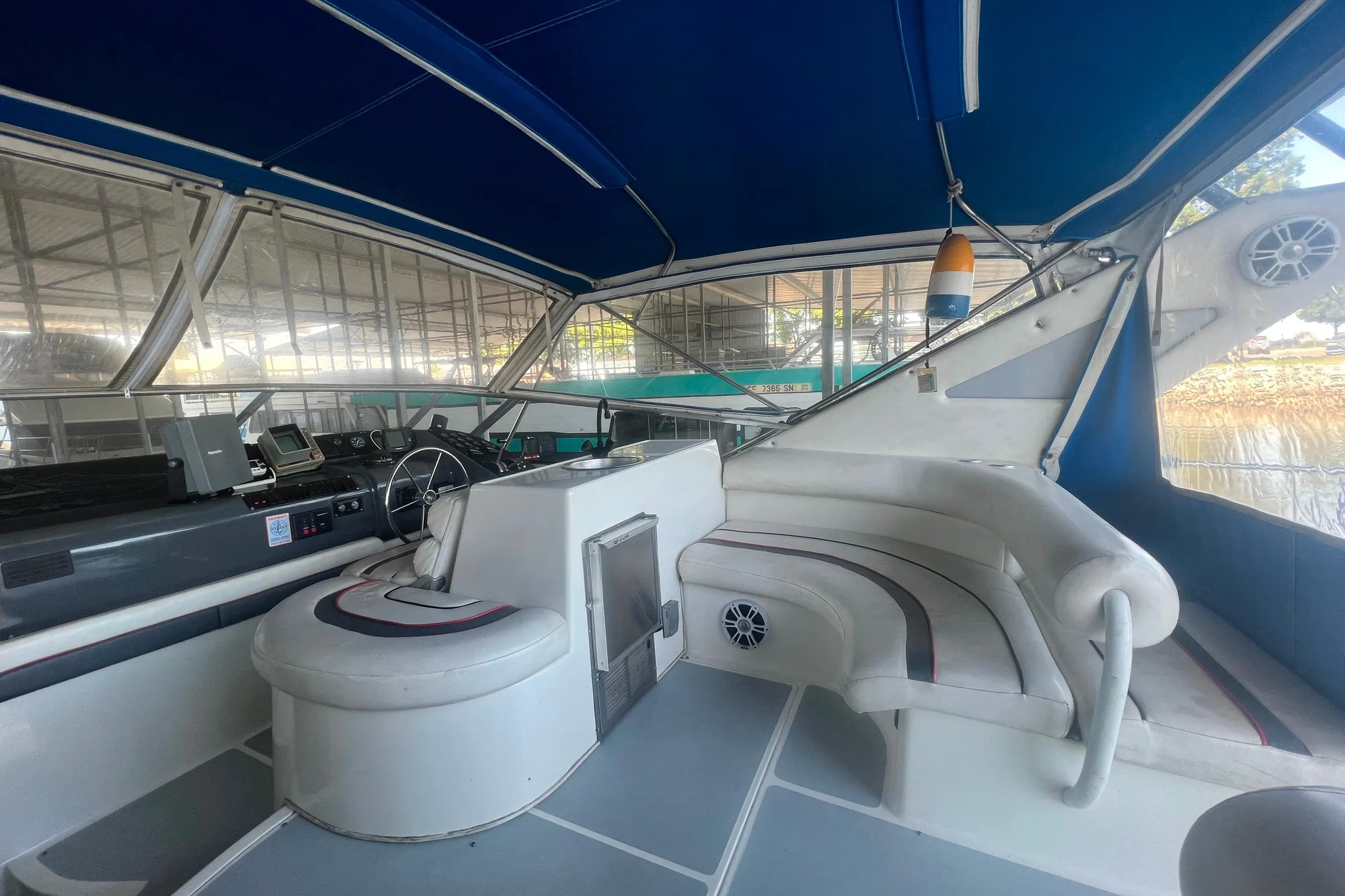 1989 Bayliner 4285 Avanti boat interior with seating and steering wheel under blue canopy.