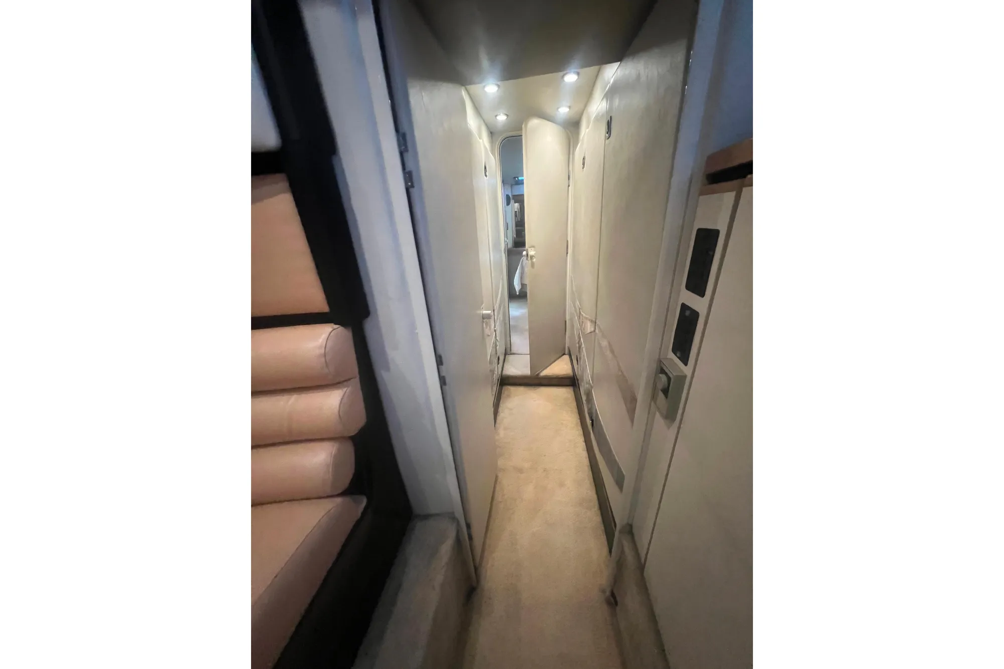 Interior hallway of 1989 Bayliner 4285 Avanti yacht, featuring beige seating and modern lighting.
