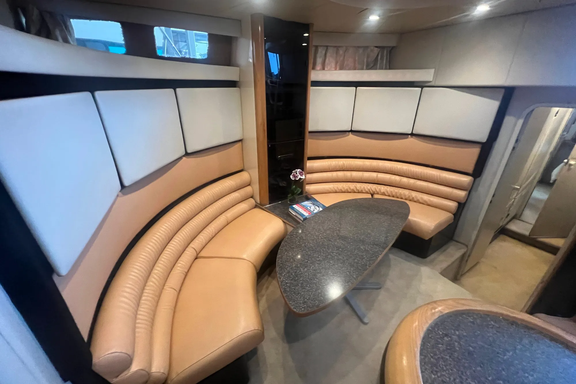 Luxurious interior of 1989 Bayliner 4285 Avanti yacht with curved seating and modern table.