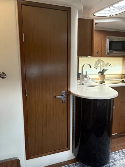 Jac & Wood Yacht Photos Pics Interior of 2017 Cruisers Yachts 380 Express, featuring a sleek kitchenette and wooden door.