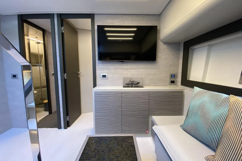  Yacht Photos Pics Modern interior of 2023 Pershing 6X yacht with TV, seating, and bathroom.