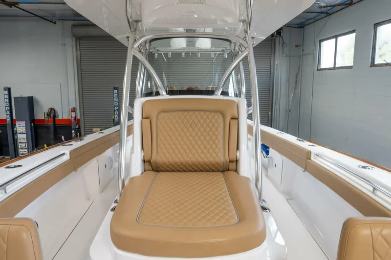 T/t Silvertime Yacht Photos Pics 2023 Valhalla Boatworks V-33 interior with tan quilted seating in a modern boat garage.