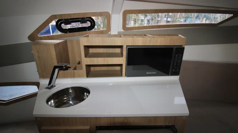  Yacht Photos Pics 2023 NX Boats 34 Sport Coupe kitchen with sink, microwave, and storage shelves.
