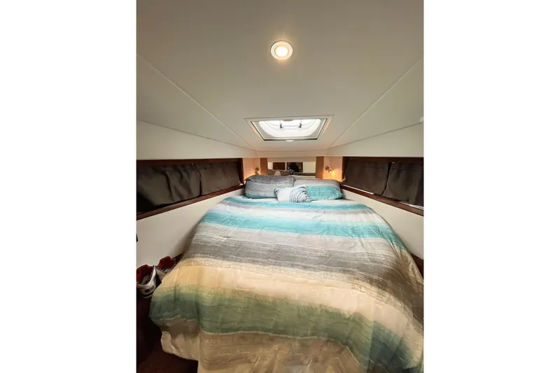  Yacht Photos Pics Cozy cabin interior of 2012 Sea Ray 390 Sundancer with skylight and striped bedding.