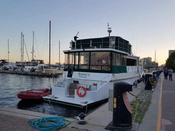 Boatel I Yacht Photos Pics Custom 65-foot trawler docked at marina, 1998 model, with lifebuoy and inflatable boat.