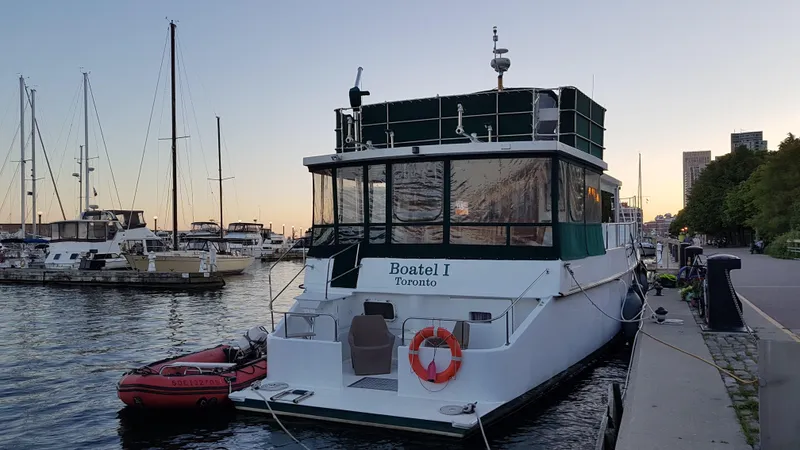 Boatel I Yacht Photos Pics Custom 65 Foot Trawler, 1998, docked at marina during sunset with lifebuoy and dinghy.