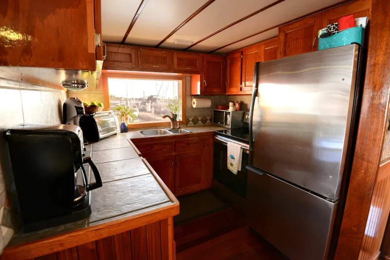Boatel I Yacht Photos Pics Kitchen interior of a 1998 Custom 65 Foot Trawler with wooden cabinets and stainless steel appliances.