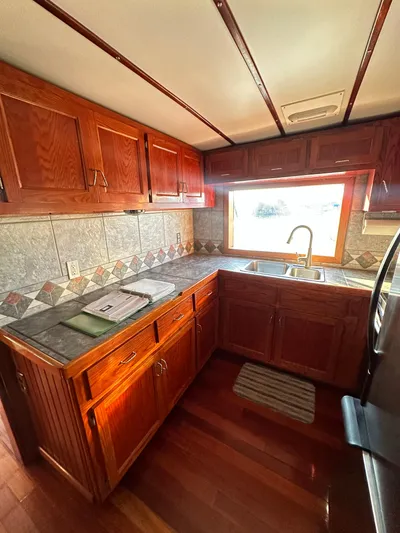 Boatel I Yacht Photos Pics Kitchen interior of a 1998 Custom 65 Foot Trawler with wooden cabinets and large window.