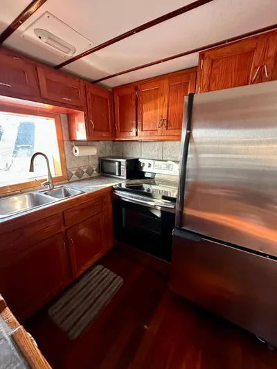 Boatel I Yacht Photos Pics Kitchen interior of a 1998 Custom 65 Foot Trawler with wooden cabinets and stainless steel appliances.