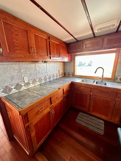 Boatel I Yacht Photos Pics Kitchen area of a 1998 Custom 65 Foot Trawler with wooden cabinets and tiled countertops.