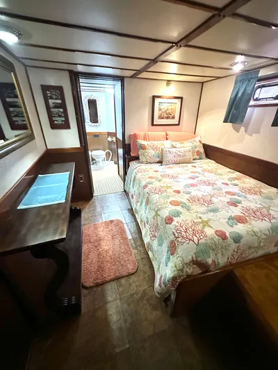 Boatel I Yacht Photos Pics Cozy bedroom in a 1998 custom 65-foot trawler with nautical decor and wooden furnishings.